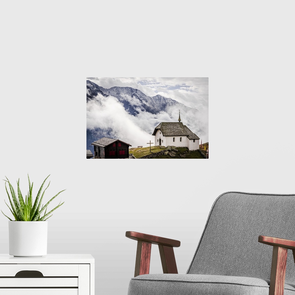 A modern room featuring Foggy sky over the small church in the alpine village of Bettmeralp, canton of Valais, Switzerlan...