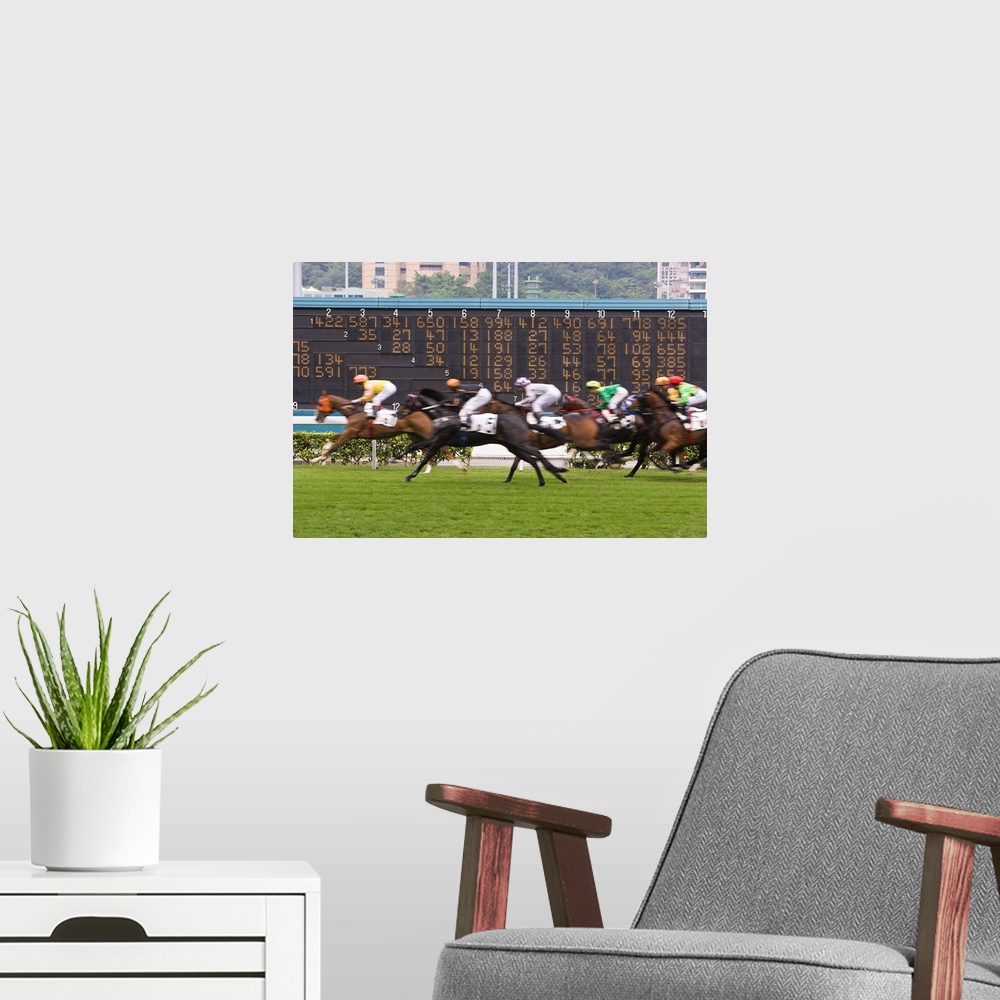 A modern room featuring Horses race past large scoreboard during race at Happy Valley racecourse, Hong Kong
