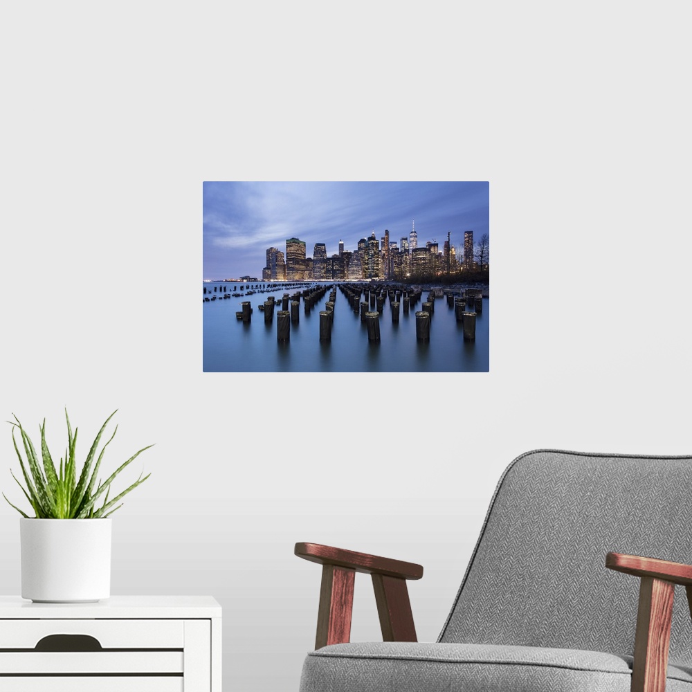 A modern room featuring Lower Manhattan skyline with wooden posts from an old pier in the foreground. New York City, New ...