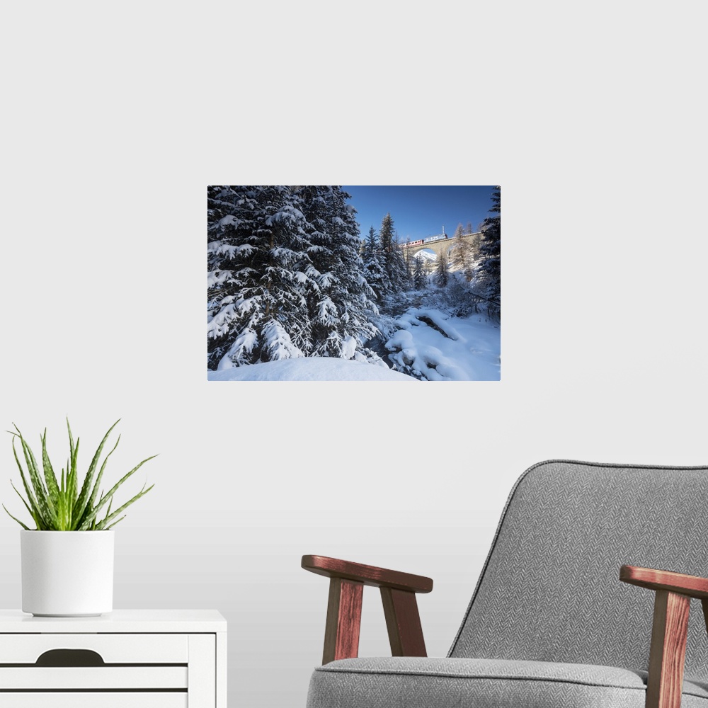 A modern room featuring Rhaetian Railway on the Chapella Viadukt surrounded by snowy woods, Canton of Graubunden, Engadin...