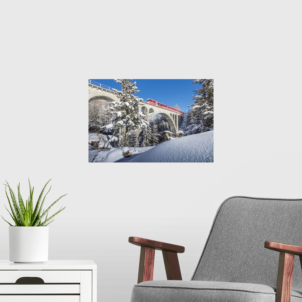A modern room featuring The red train on viaduct surrounded by snowy woods, Cinuos-Chel, Canton of Graubunden, Engadine, ...