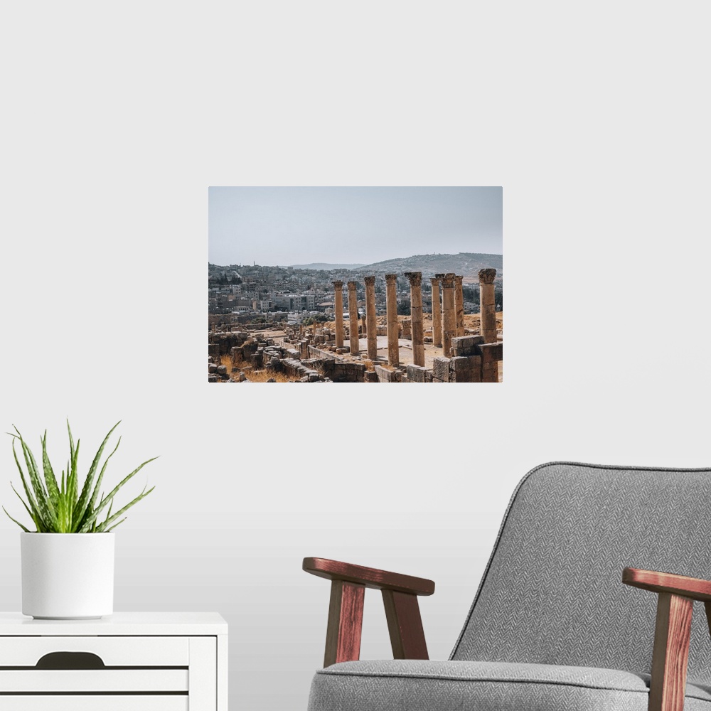 A modern room featuring The ruins of a Roman temple, with the modern city of Jerash in the background, Jerash, Jordan, Mi...