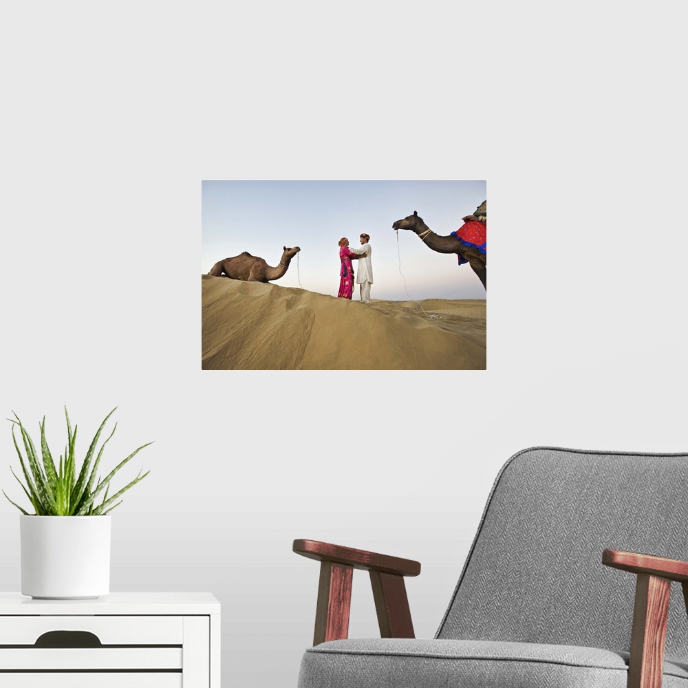 A modern room featuring Bride and groom with camels in sand dunes, Rajistan, India
