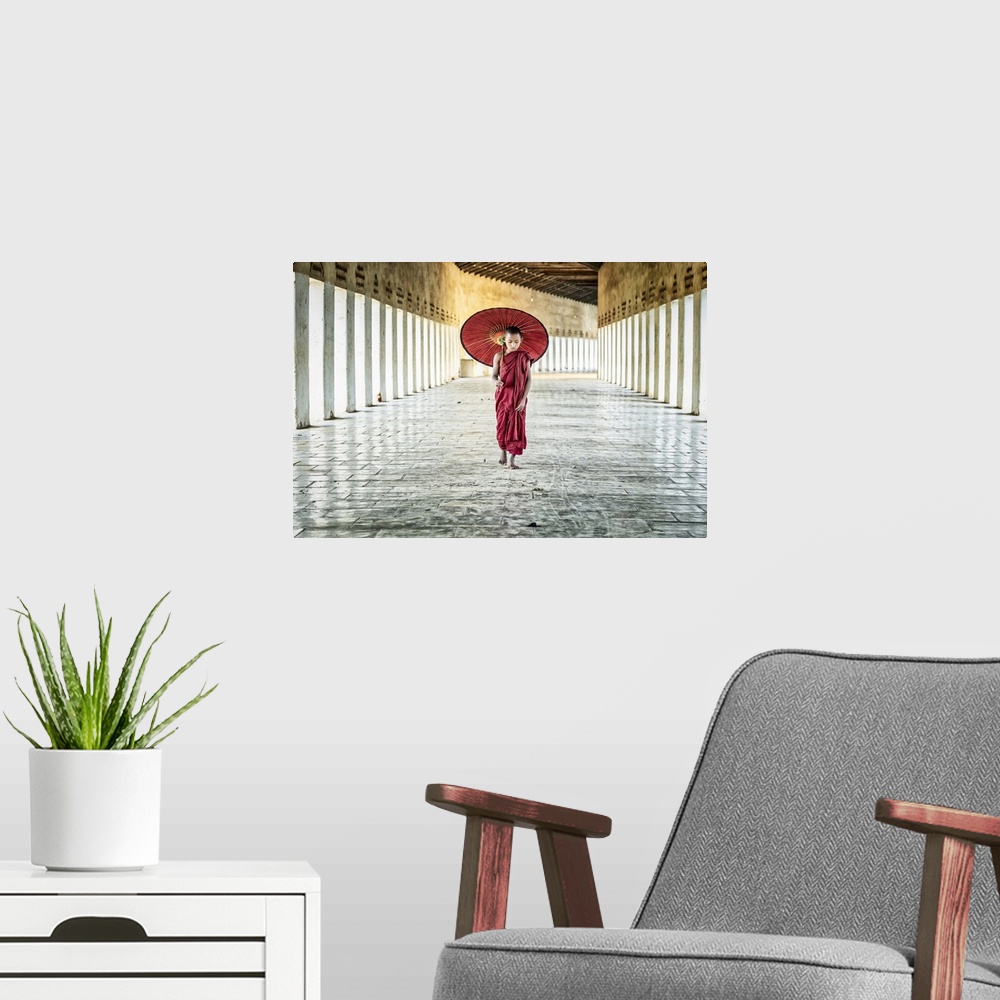 A modern room featuring Burmese monk with parasol walking in his monastery