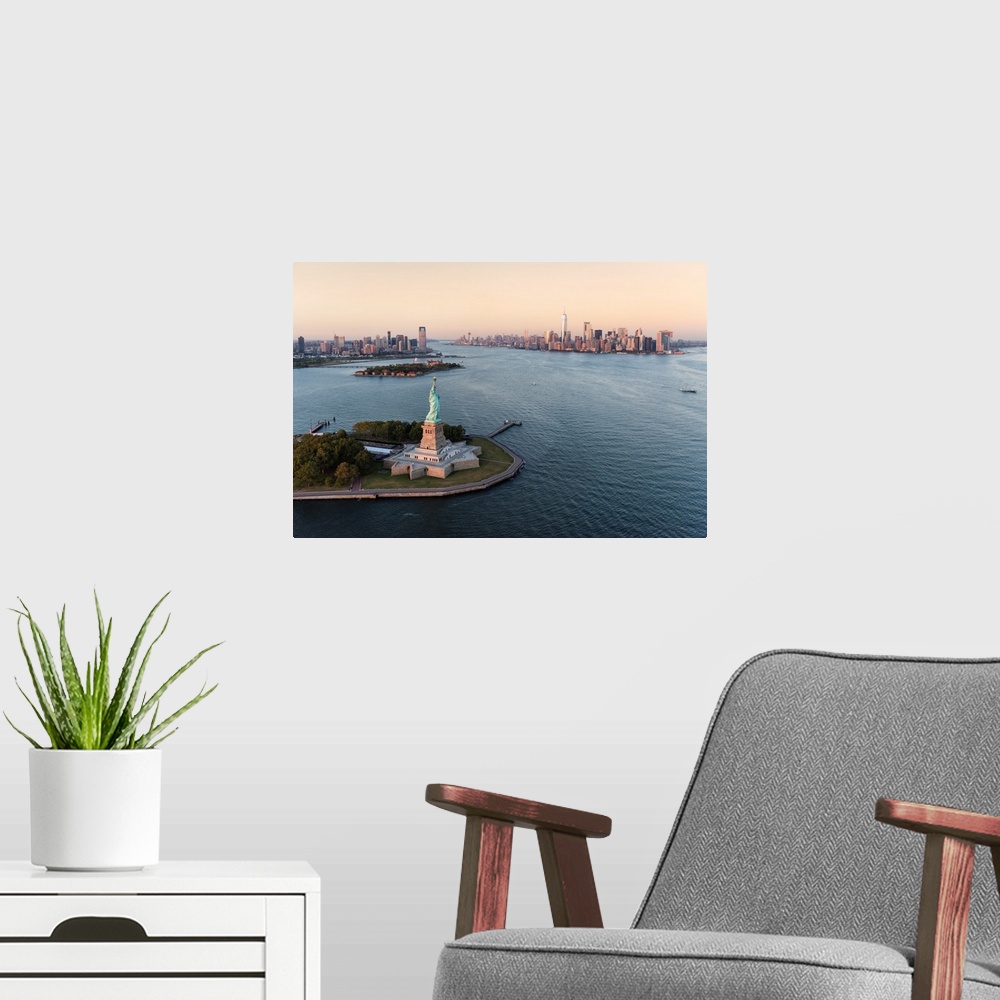 A modern room featuring Stature of Liberty and Manhattan from above at sunset