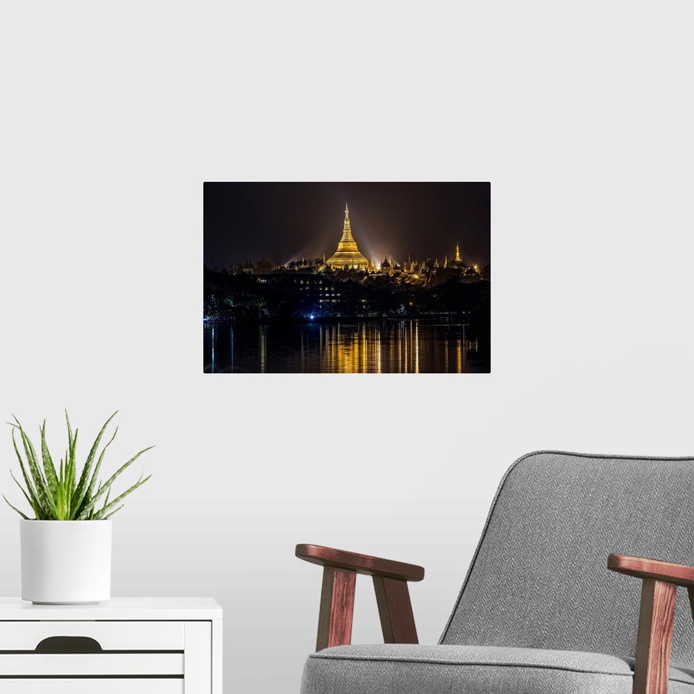 A modern room featuring The Shwedagon Pagoda reflecting in the water after dark in Yangon.