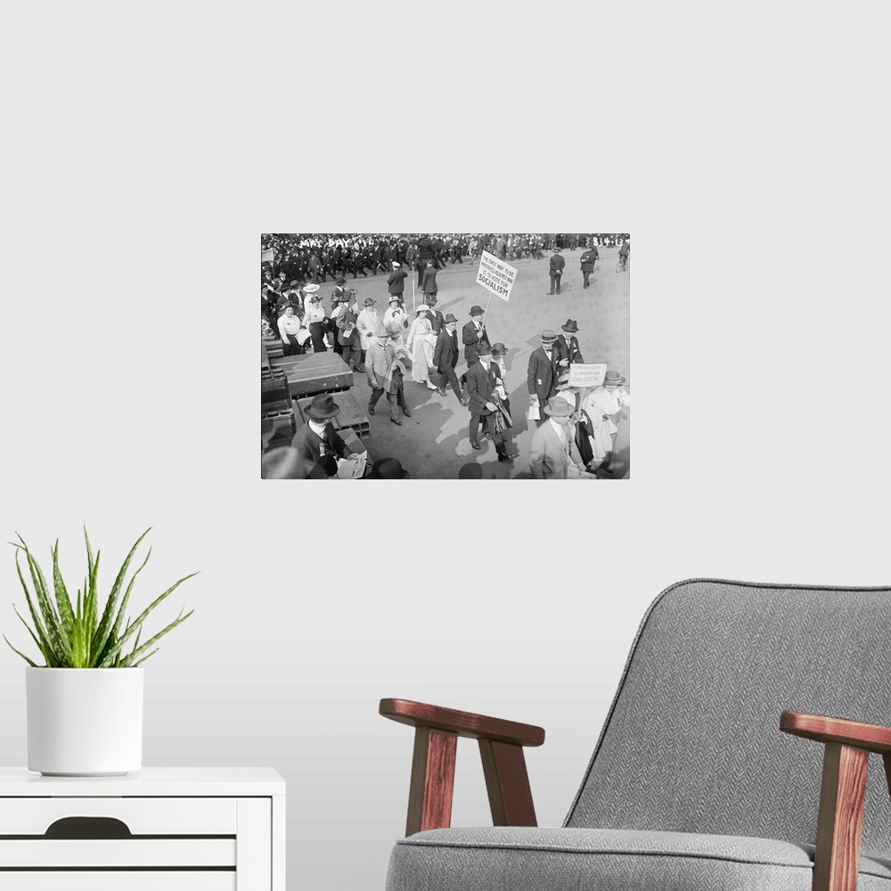 A modern room featuring Women and men marching at the May Day Parade as one man holds a sign promoting Socialism in New Y...