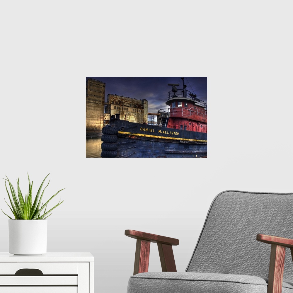 A modern room featuring An old tug boat near to industrial buildings