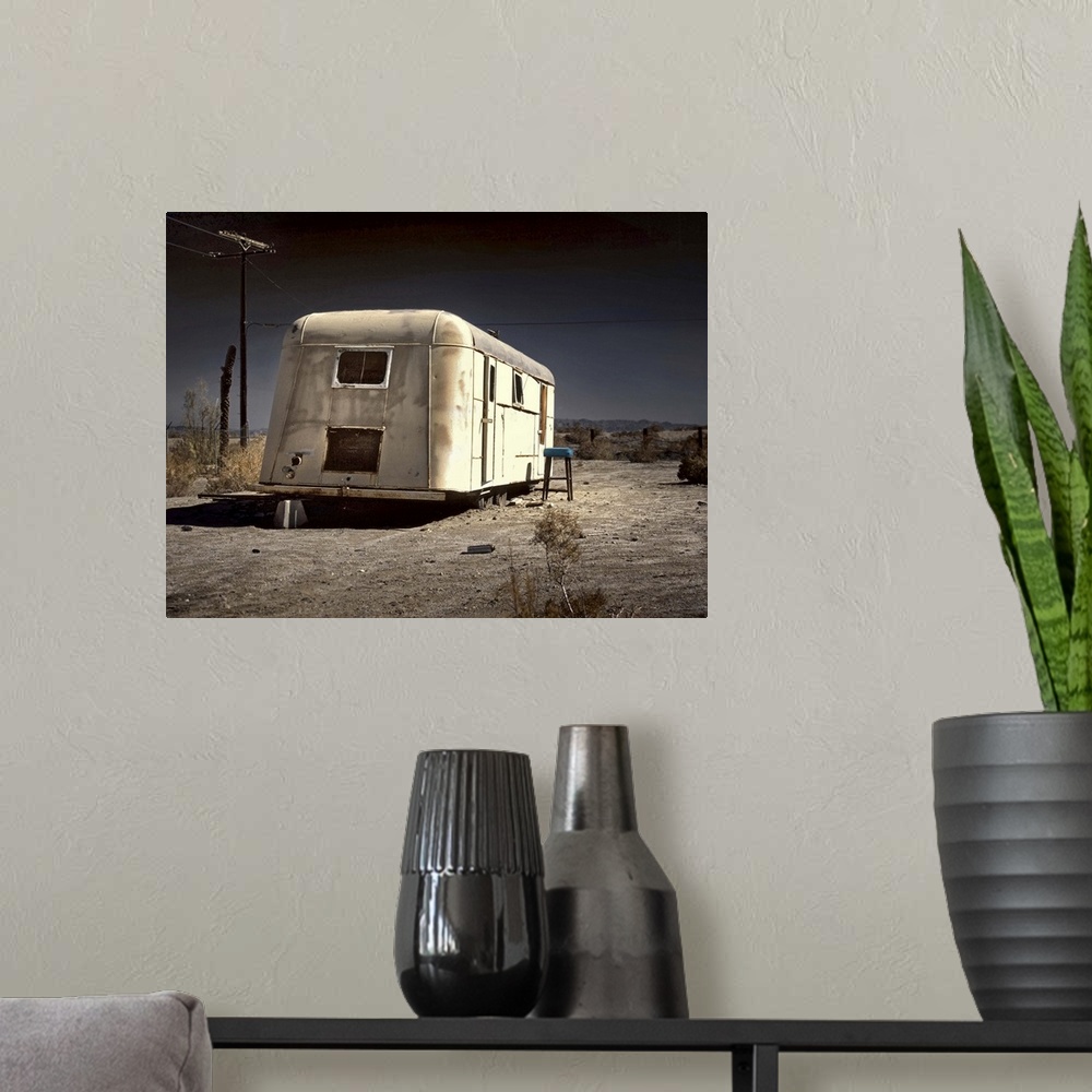 A modern room featuring An old white caravan left to rot in the desert