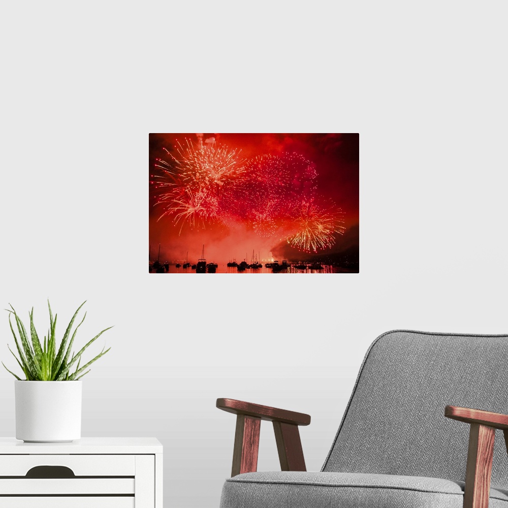 A modern room featuring Fireworks and boats in the ocean against a red sky