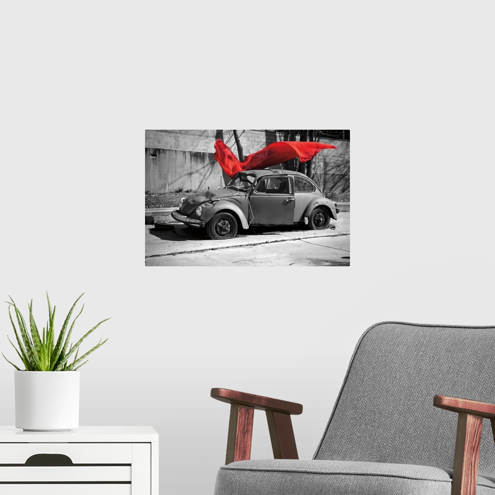 A modern room featuring A black and white photograph of a car with a colorized red cloth hanging in the air.