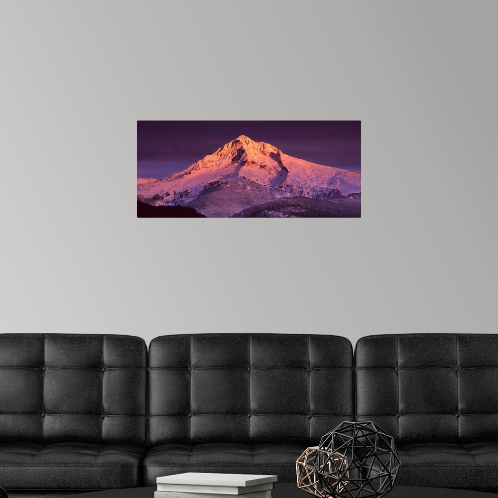 A modern room featuring Mount Hood illuminated in sunset colors at dusk.