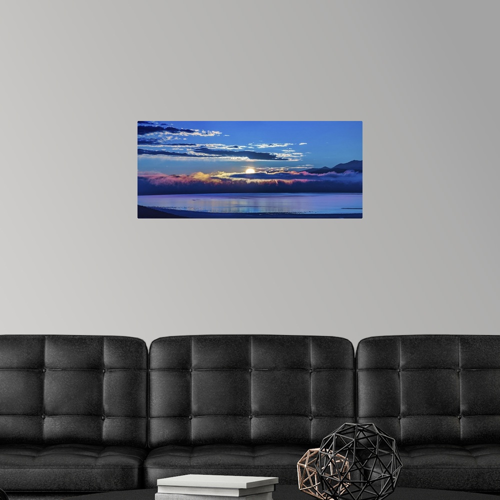 A modern room featuring The sun peeking behind the clouds at dawn over Mono Lake, California.