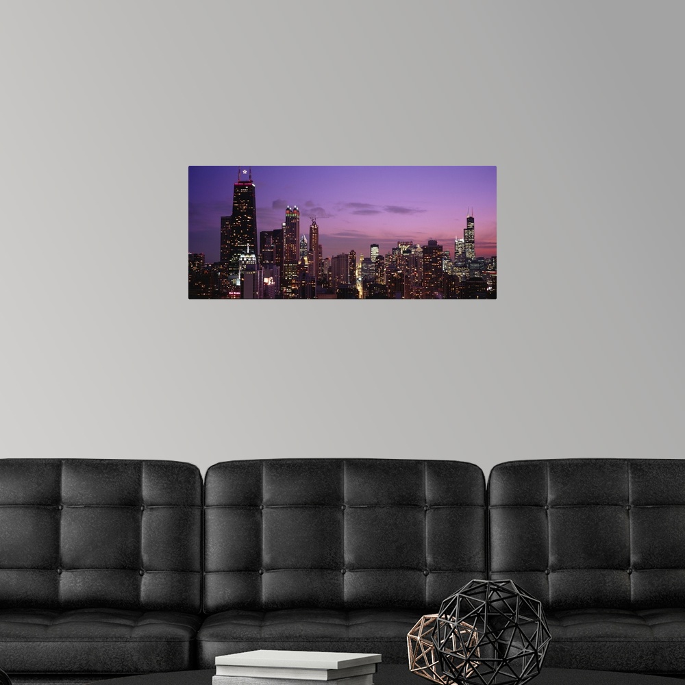 A modern room featuring Dusk panoramic shot of the tops of lit up buildings in downtown Chicago.