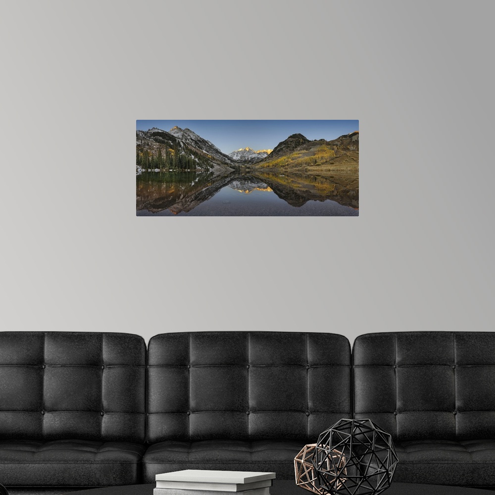 A modern room featuring Panoramic photograph shows a mountain range filled with patches of snow and trees as they perfect...