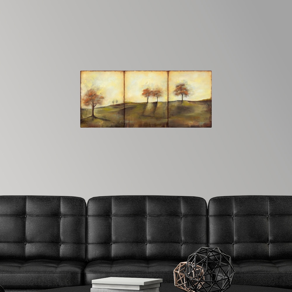 A modern room featuring Triptych painting of a countryside meadow in the fall, with small groups of trees.