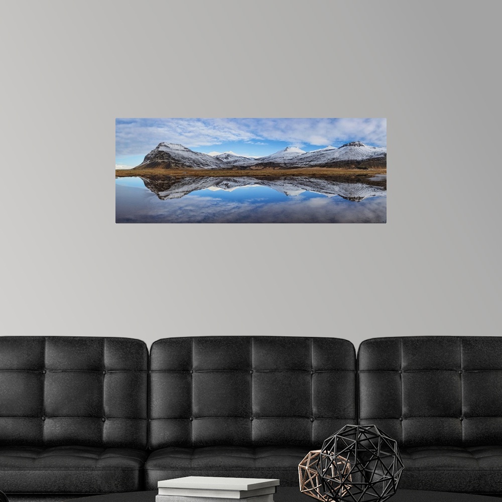 A modern room featuring Snow covered mountain panorama reflecting in a lake in Iceland.