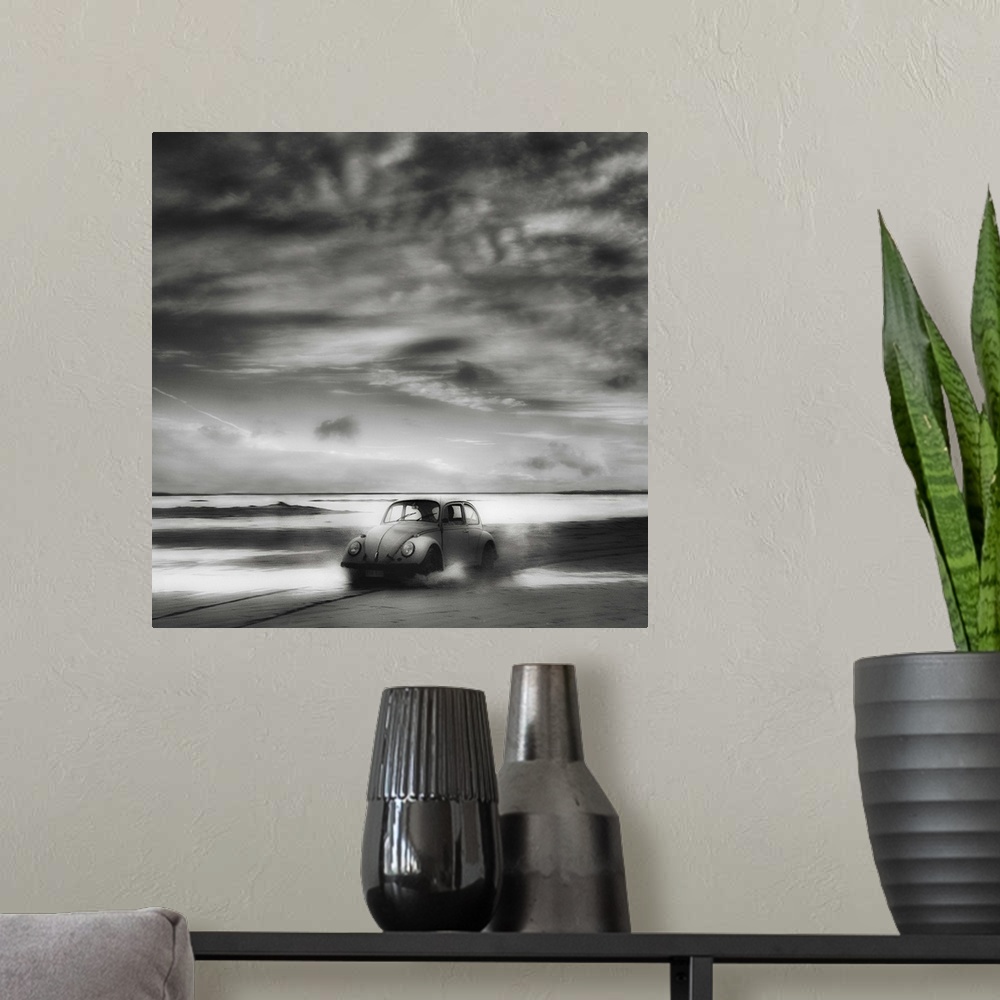 A modern room featuring A Volkswagen Beetle driving down a sandy beach with stunning clouds overhead.