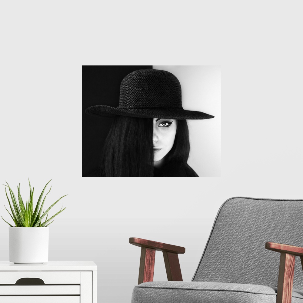 A modern room featuring Portrait of a woman with face half obscured, wearing a large hat.