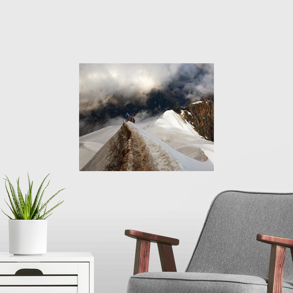 A modern room featuring Mountain climbers trekking across a snowy peak on their way to mountains obscured by clouds.