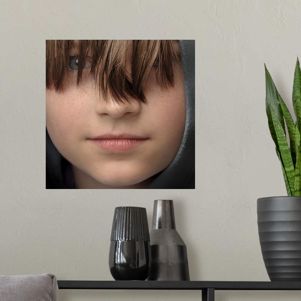 A modern room featuring Close-up portrait of a young boy with long bangs covering his eyes.