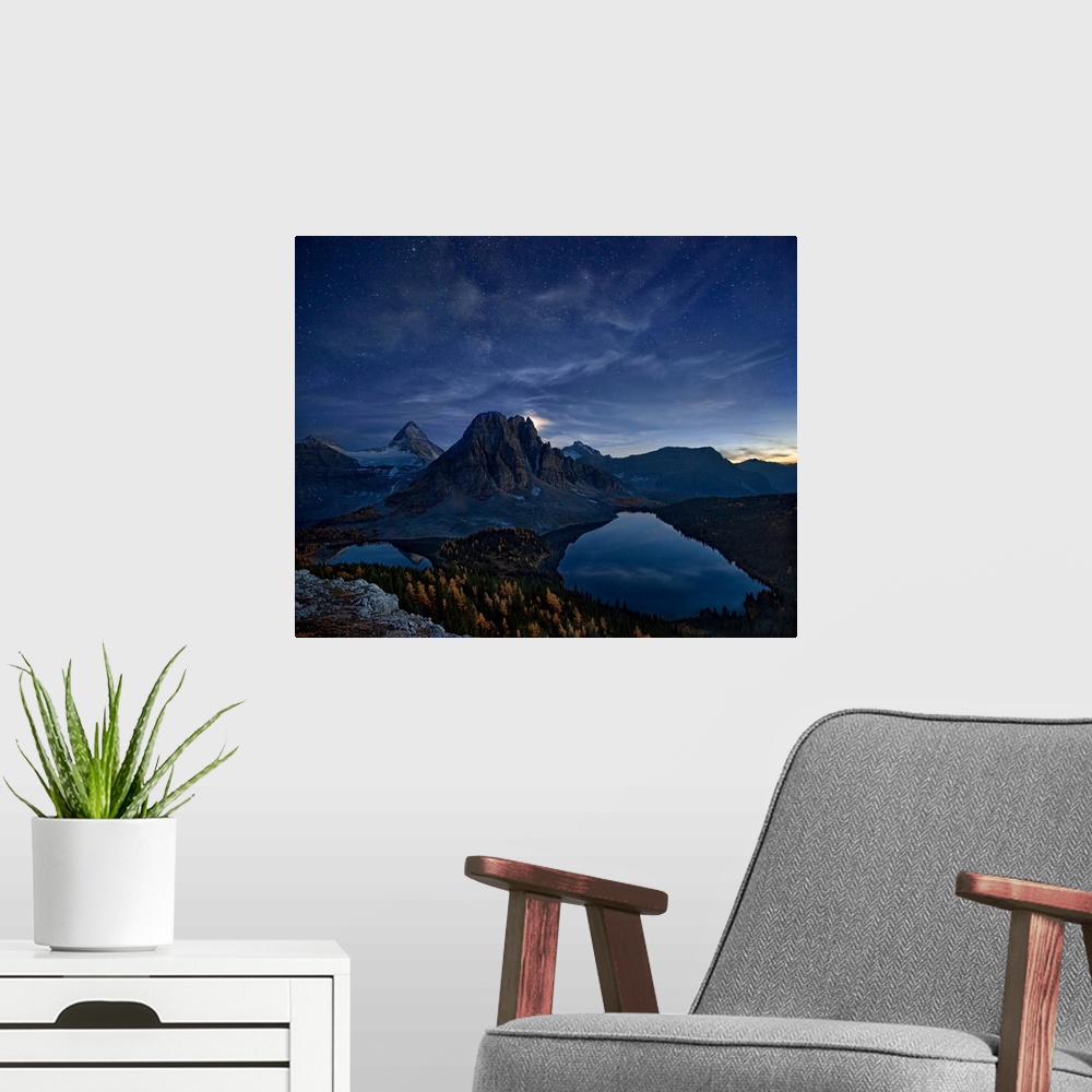A modern room featuring Mount Assiniboine in the Canadian Rockies at night, under a starry sky.