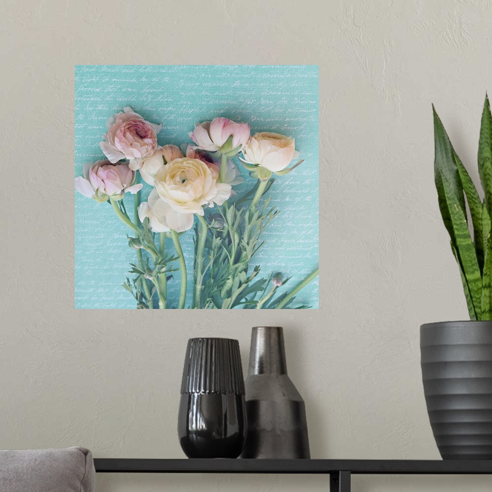 A modern room featuring Square photograph of pink and white peonies with long, leafy stems laying on a light blue backgro...