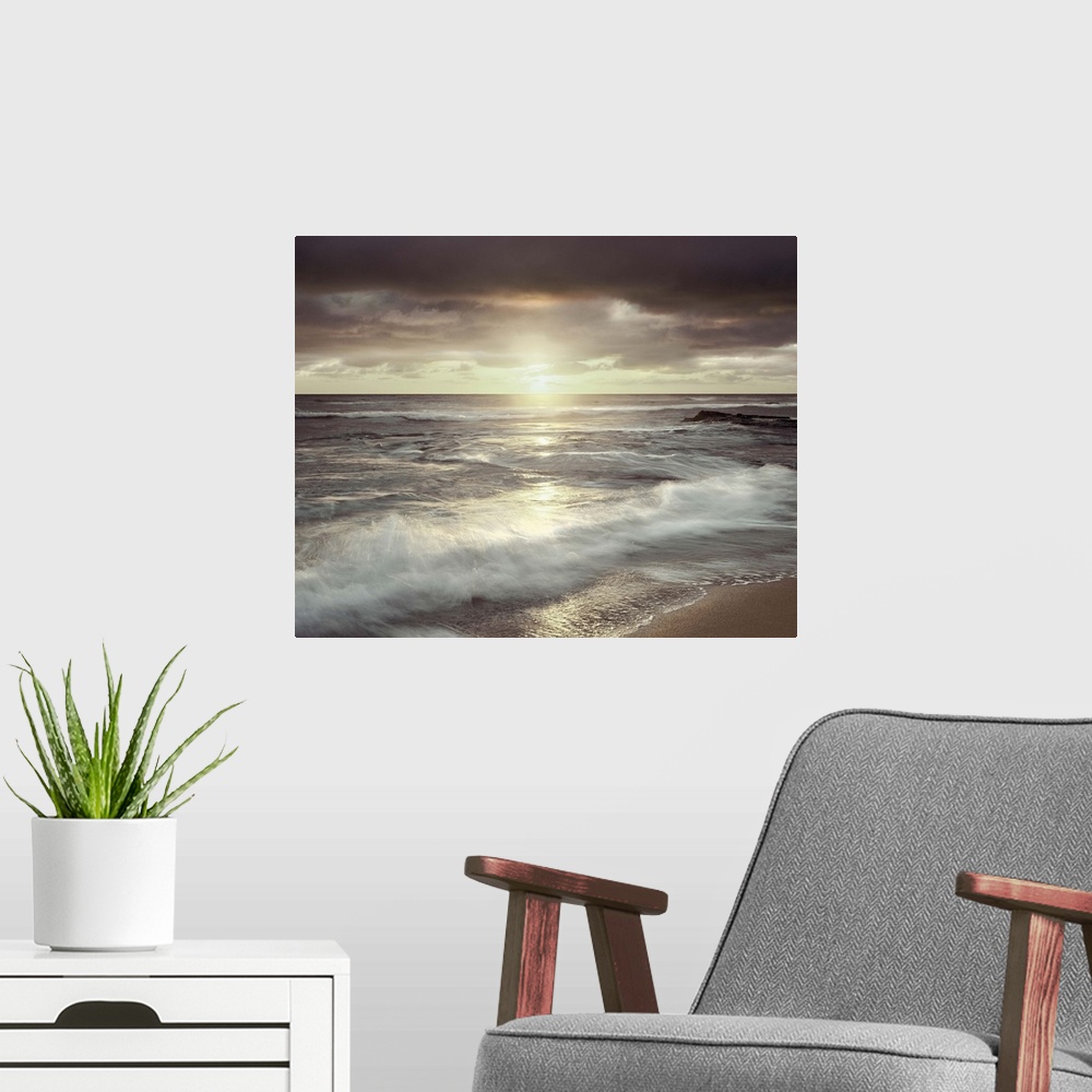 A modern room featuring Long exposure photograph of waves crashing on the shore with an evening sunset and a cloudy sky.