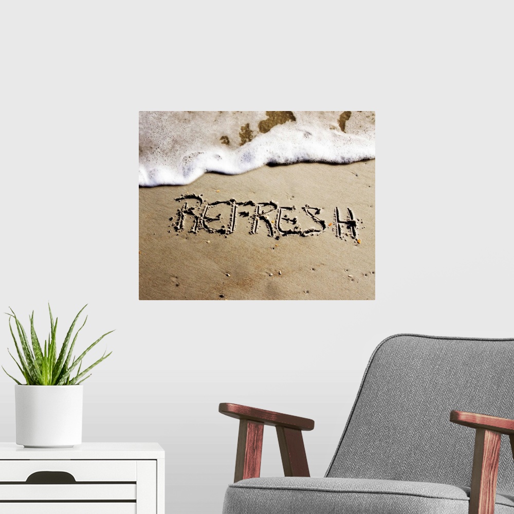 A modern room featuring The word "Refresh" drawn in the sand near the ocean water.