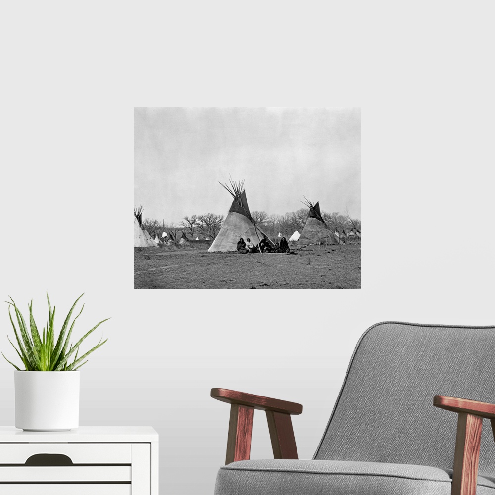 A modern room featuring A Comanche Indian family sits outside their teepee in the Iron Mountain's Camp, 1873.
