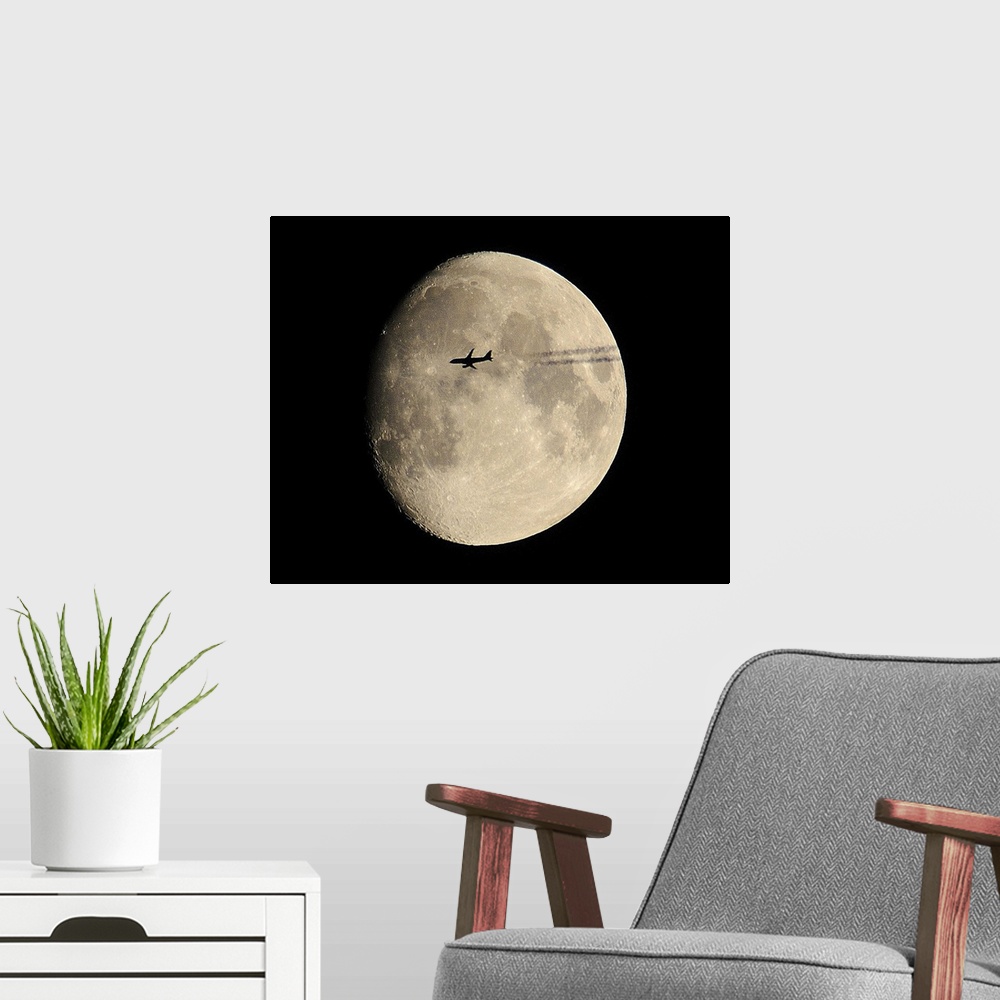 A modern room featuring plane crossing in front of moon.