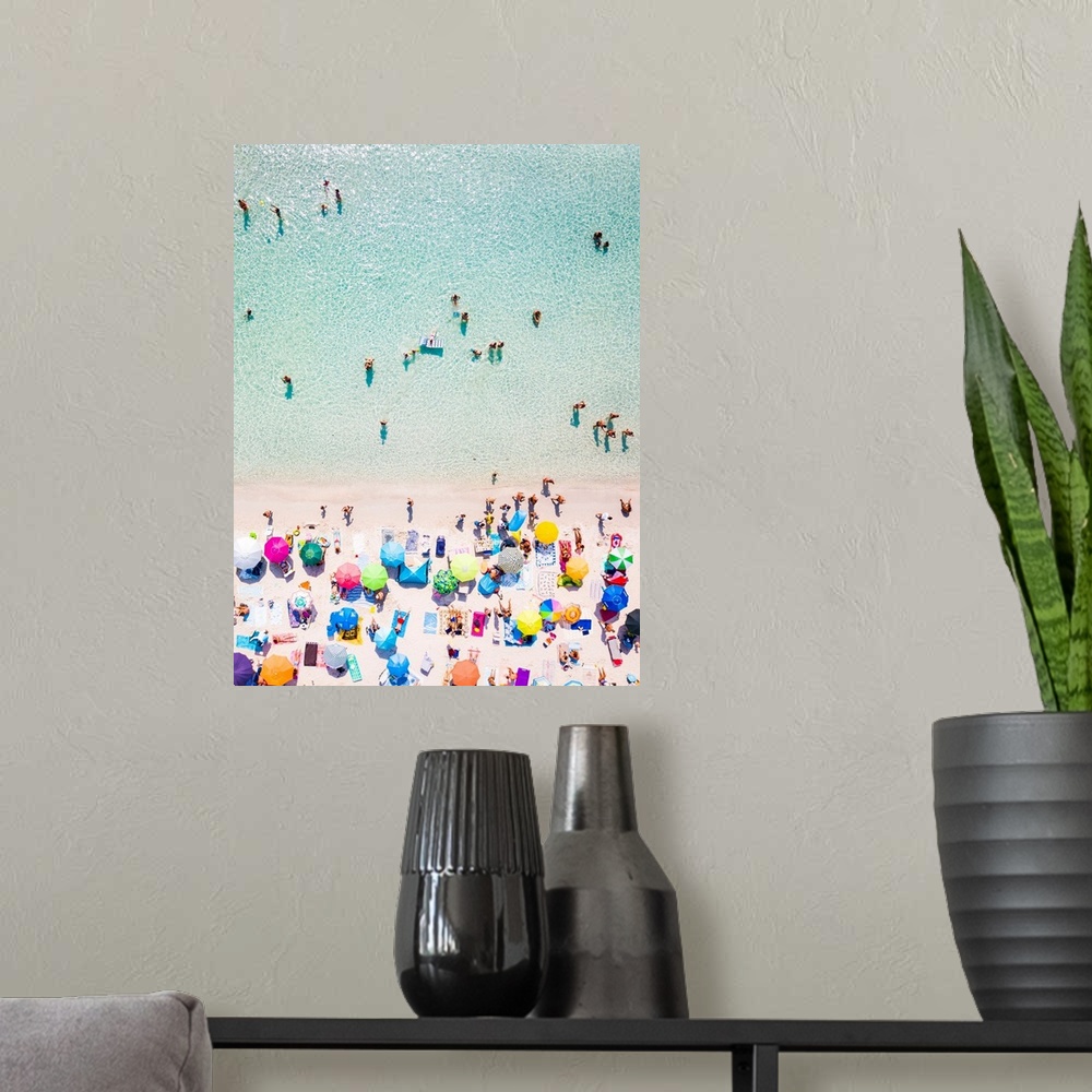 A modern room featuring Aerial view of a white beach full of colored beach umbrellas and relaxed people swimming on a cle...