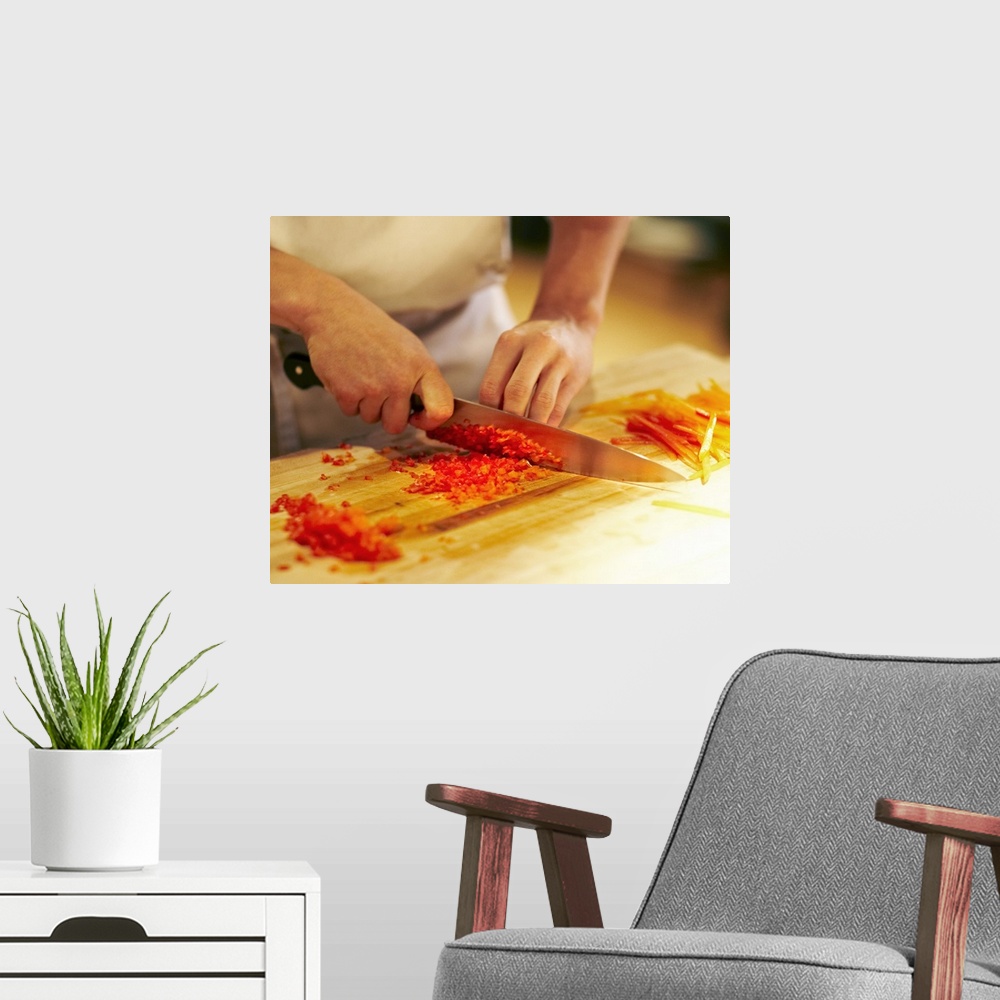 A modern room featuring Chef mincing bell peppers with knife