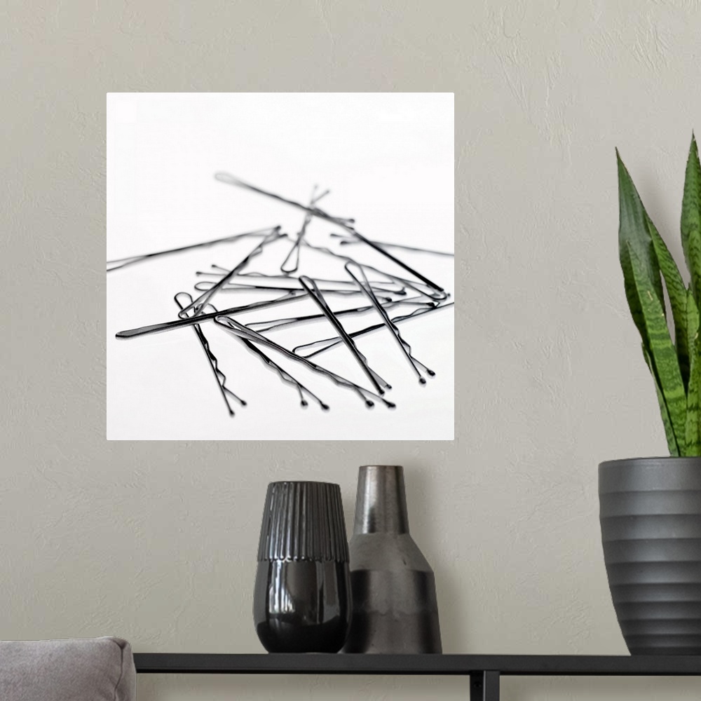 A modern room featuring Square, large close up photograph of a small pile of hair pins or bobby pins, on a plain white ba...