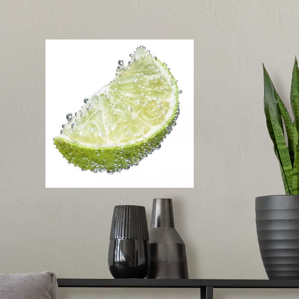 A modern room featuring A juicy ripe organic lime wedge fruit submerged in clean clear refreshing water and covered in bu...