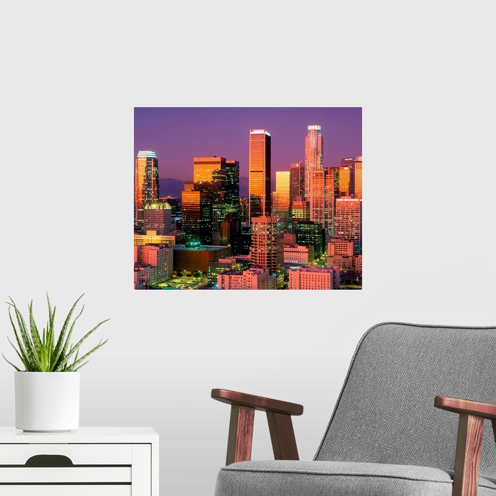 A modern room featuring Landscape, close up photograph on a large wall hanging of brightly lit skyscrapers in downtown Lo...