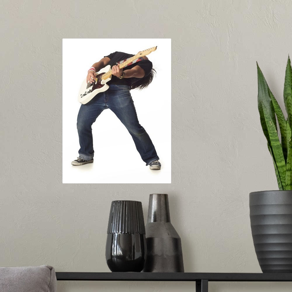 A modern room featuring an asian male teen in jeans and a black shirt leans back while playing an electric guitar