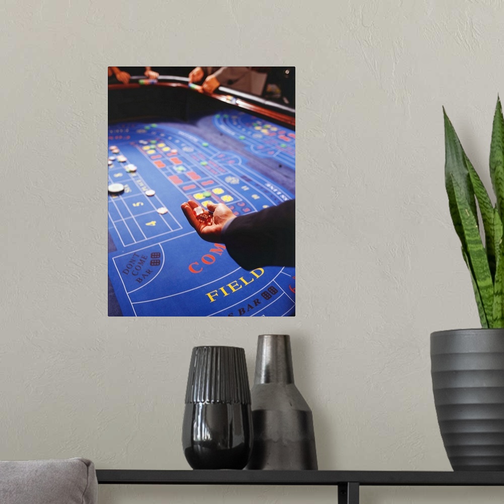 A modern room featuring Man shaking dice during game of craps in casino