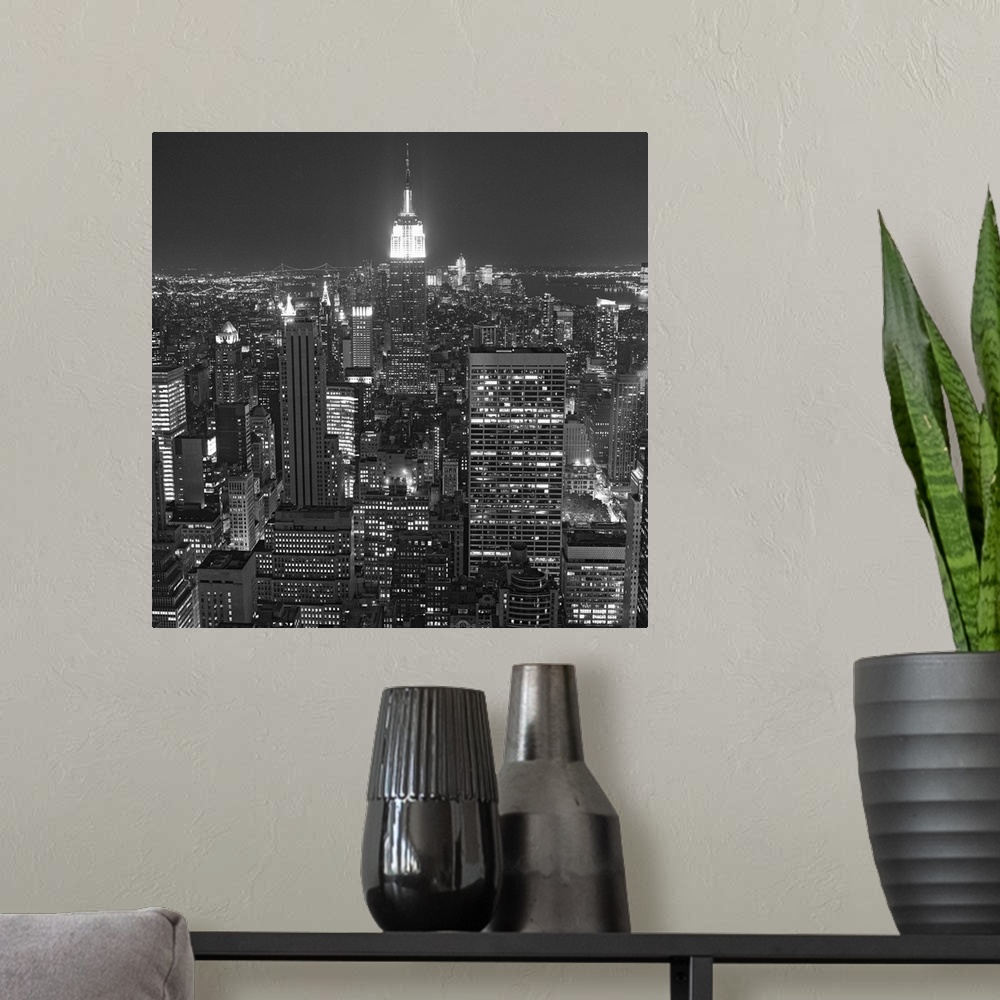 A modern room featuring Photograph of skyscrapers and skyline lit up after dark in the "Big Apple."
