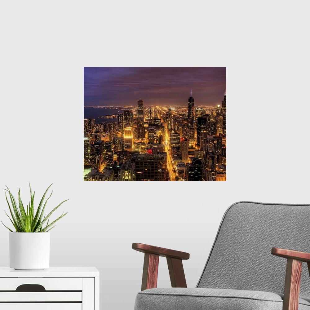 A modern room featuring High-angle photograph of city with buildings and streets lit up at dusk.