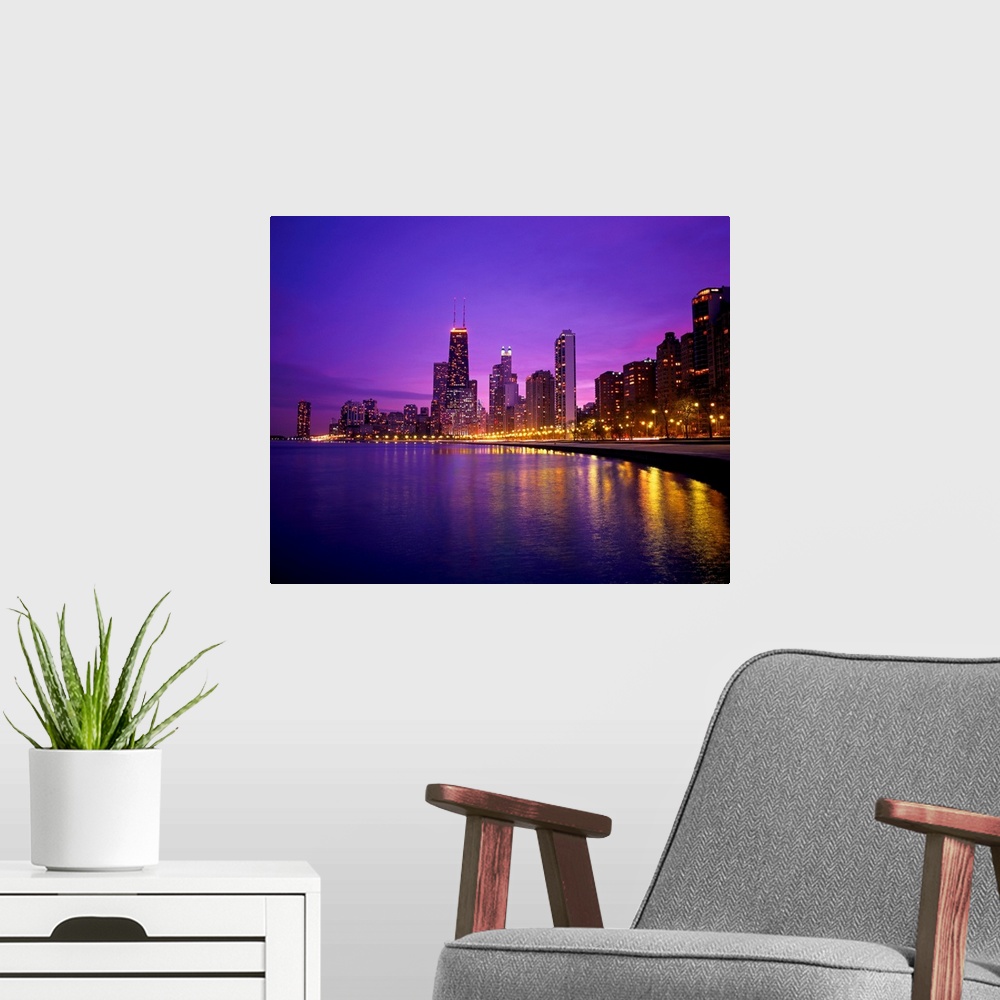 A modern room featuring Photograph of cityscape and waterfront at night.  The buildings are lit up and the lights are ref...