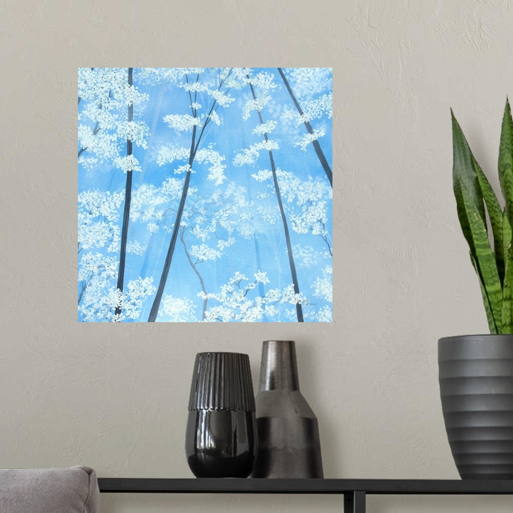 A modern room featuring Impressionist painting looking up at white blossomed tree tops with a sky blue background.