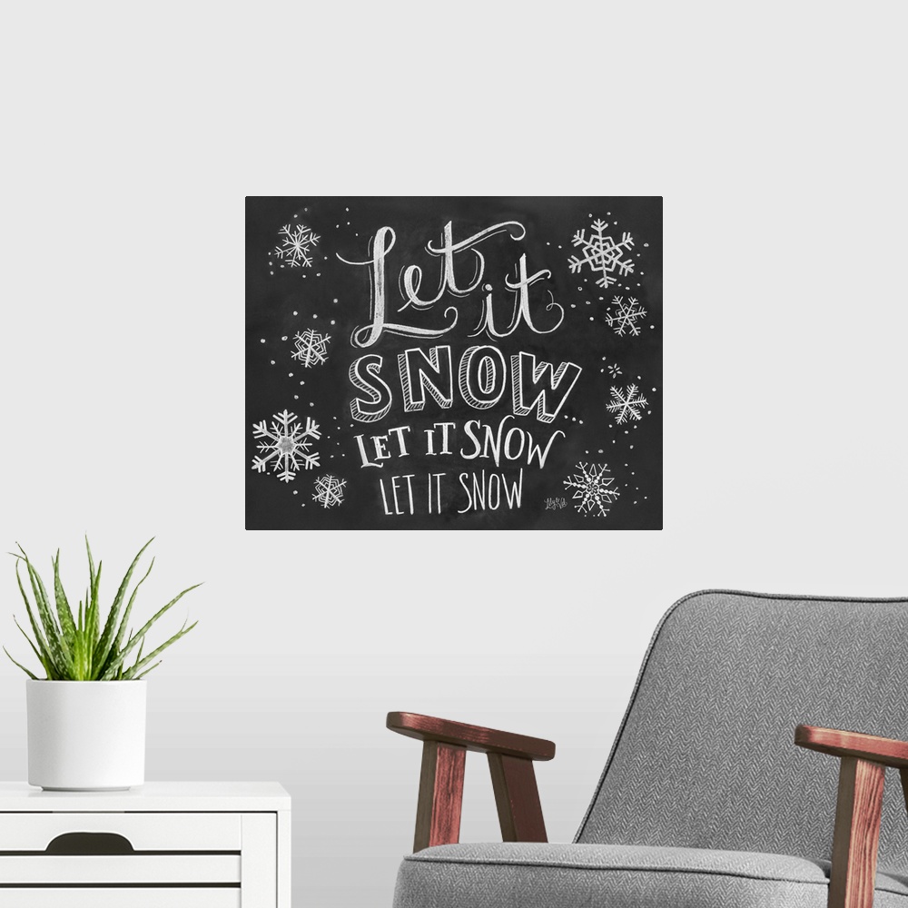 A modern room featuring "Let it snow" handwritten with several snowflakes in white chalk on a black background.