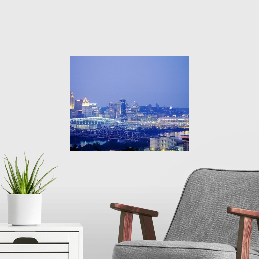A modern room featuring A photograph of a bridge, stadium, and the cityos downtown illuminated at night.