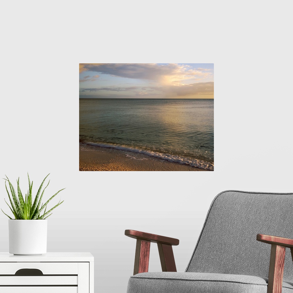 A modern room featuring Giant photograph shows the calm waters of a coastline as they gently crash against the sandy shor...