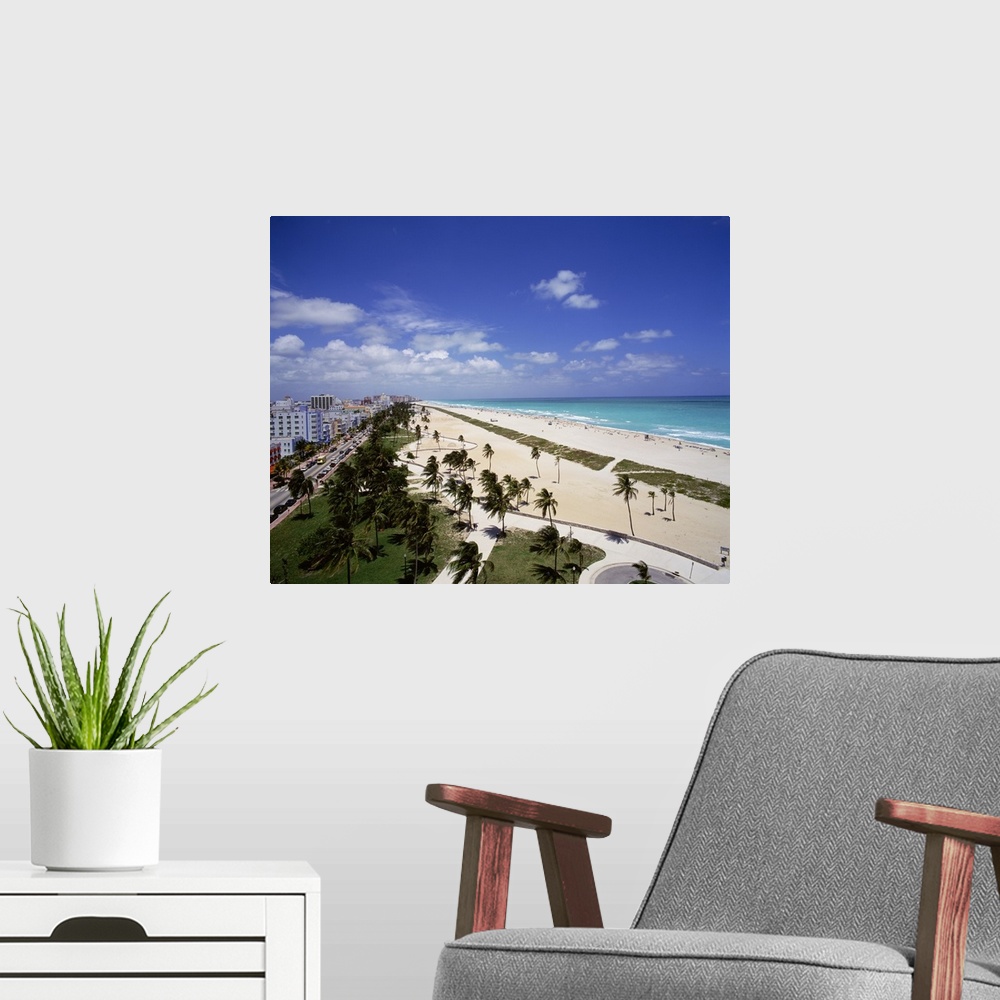 A modern room featuring Canvas photo art of a city and street on the left meeting white sand and ocean on the right with ...