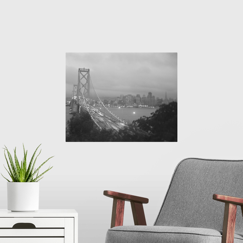 A modern room featuring This photograph is of the golden gate bridge lit up at night with the cars lights streaking by an...