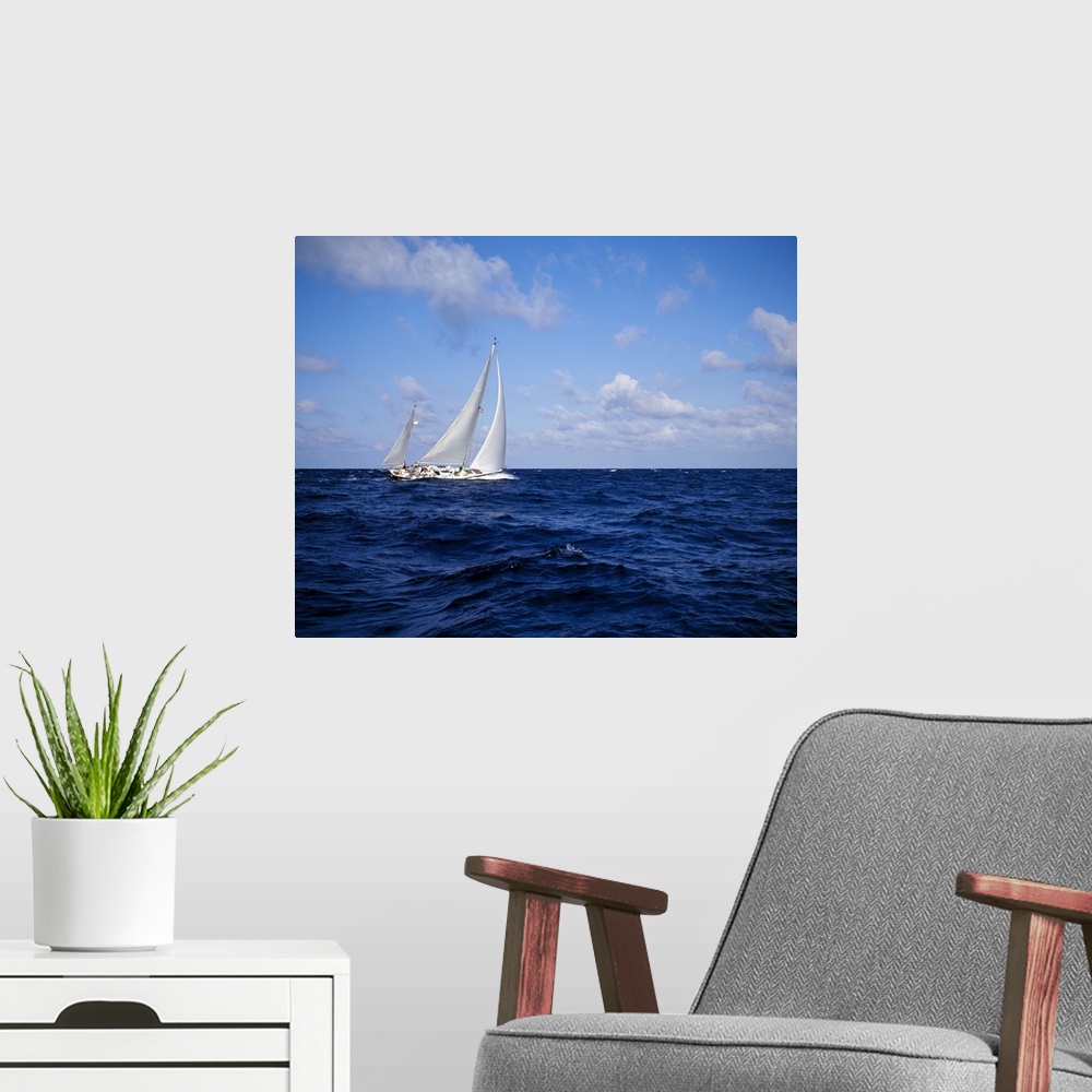 A modern room featuring A single sail boat is photographed on rough ocean water with a cloudy sky above.