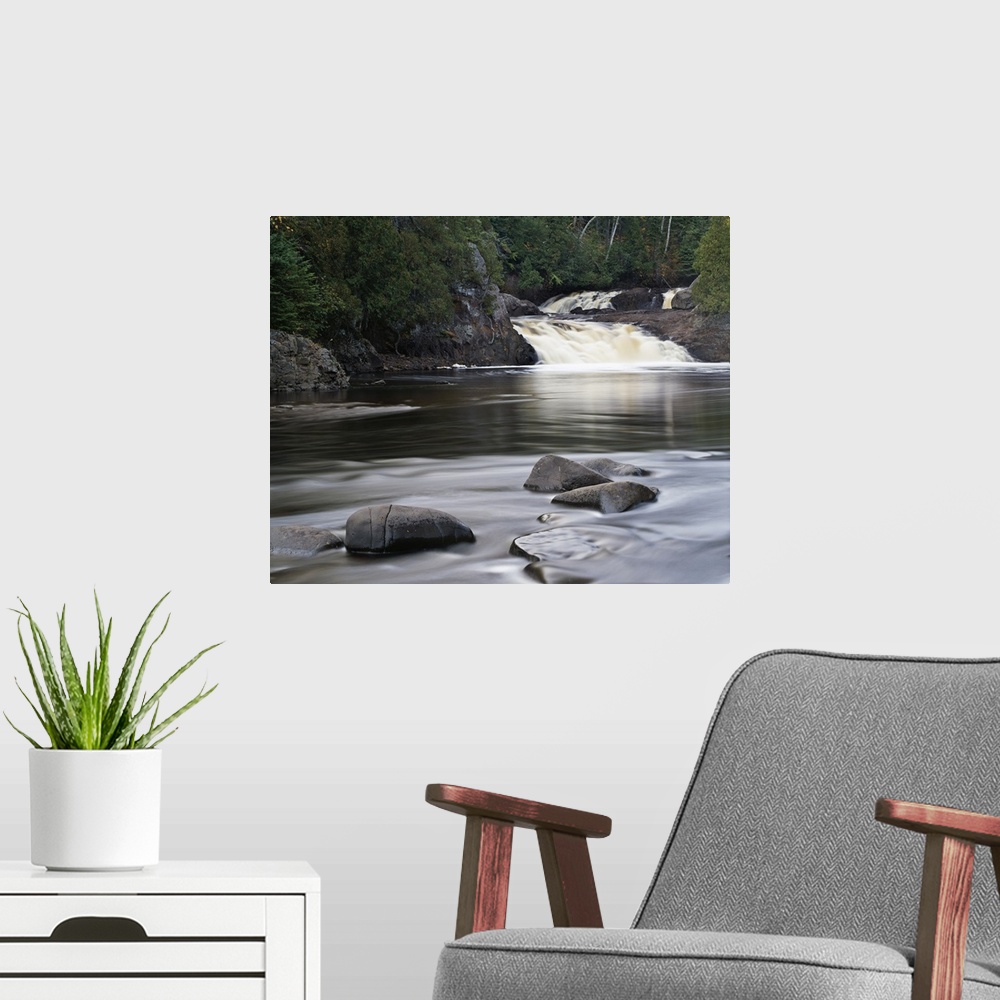 A modern room featuring Photograph of two falls flowing into a river that is lined with cliffs and trees on the back side...