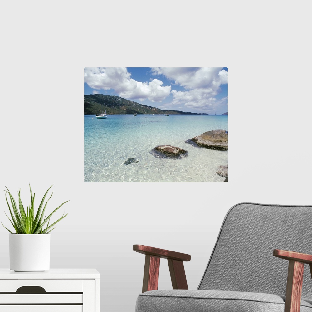 A modern room featuring Big photo print of boats floating near the shore of a clear ocean with hills in the background.